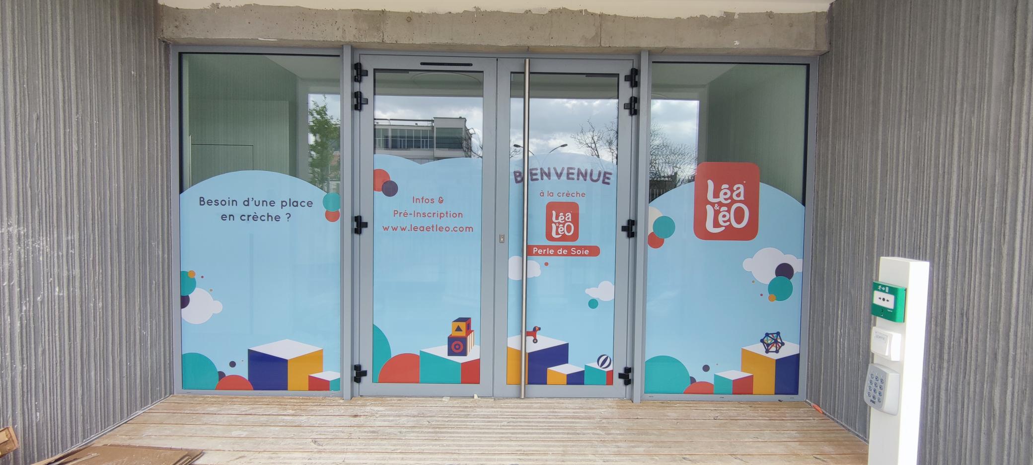 vitrophanie-vitrine-creche-habillee-avec-logo-et-jouet-fond-bleu